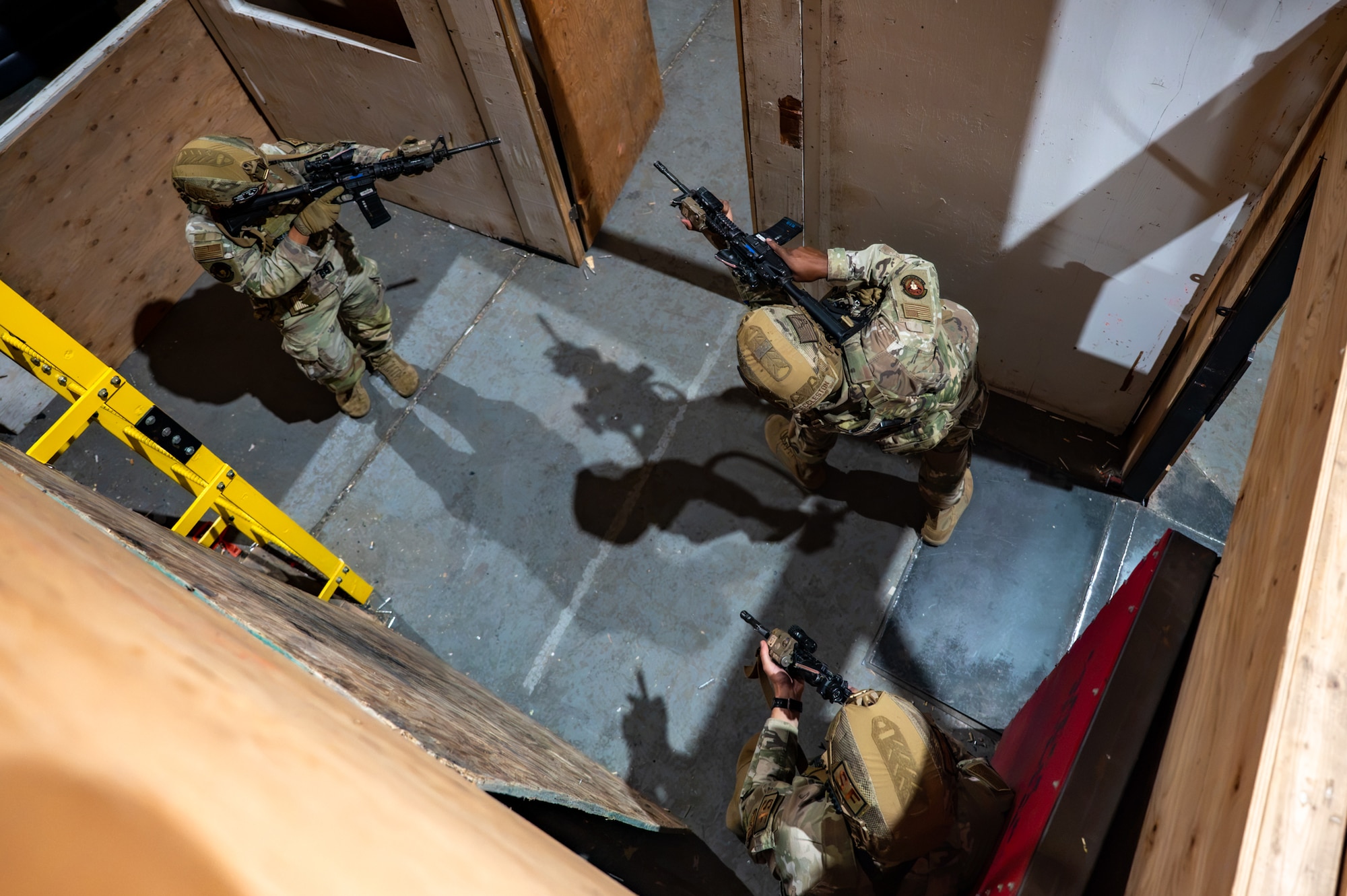 A group of uniformed personnel execute room-clearing procedures during a training exercise.