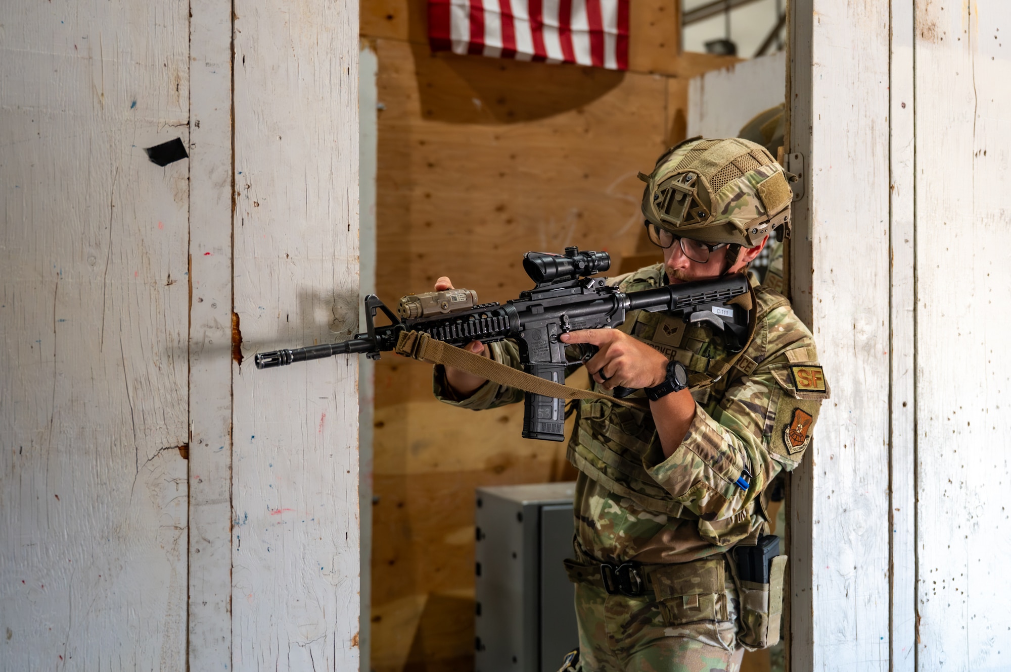 A uniformed man guards a door while holding a rifle.