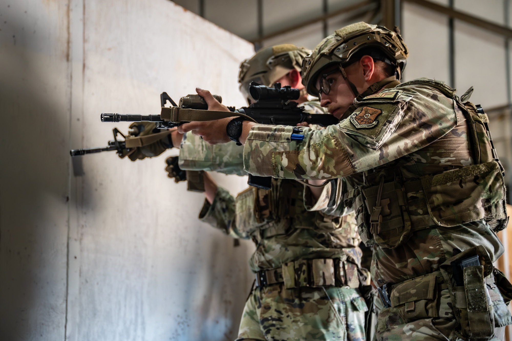 A group of uniformed personnel form a stack while holding rifles during a training exercise.