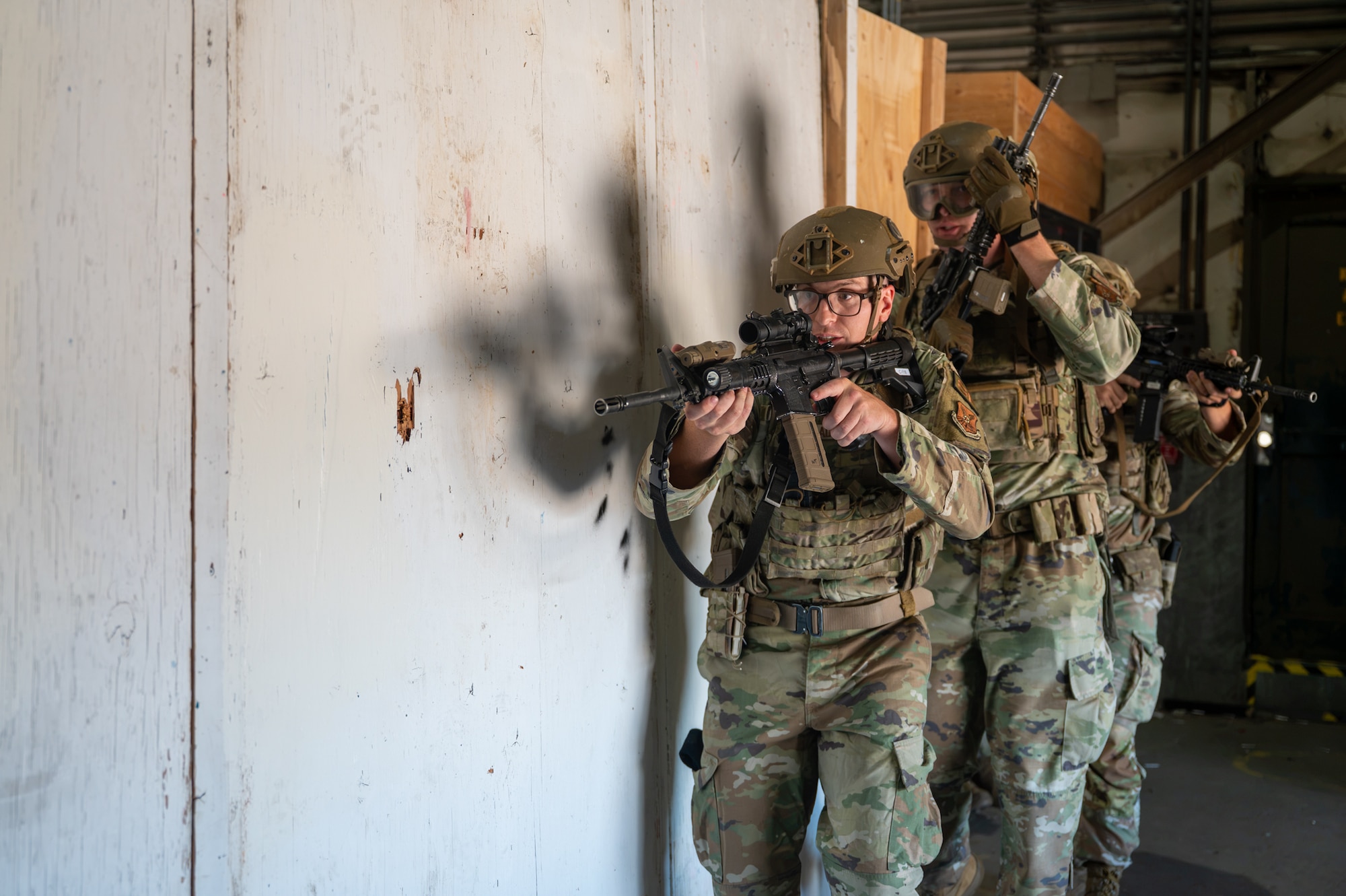 A group of uniformed personnel move in formation with rifles during a training exercise.