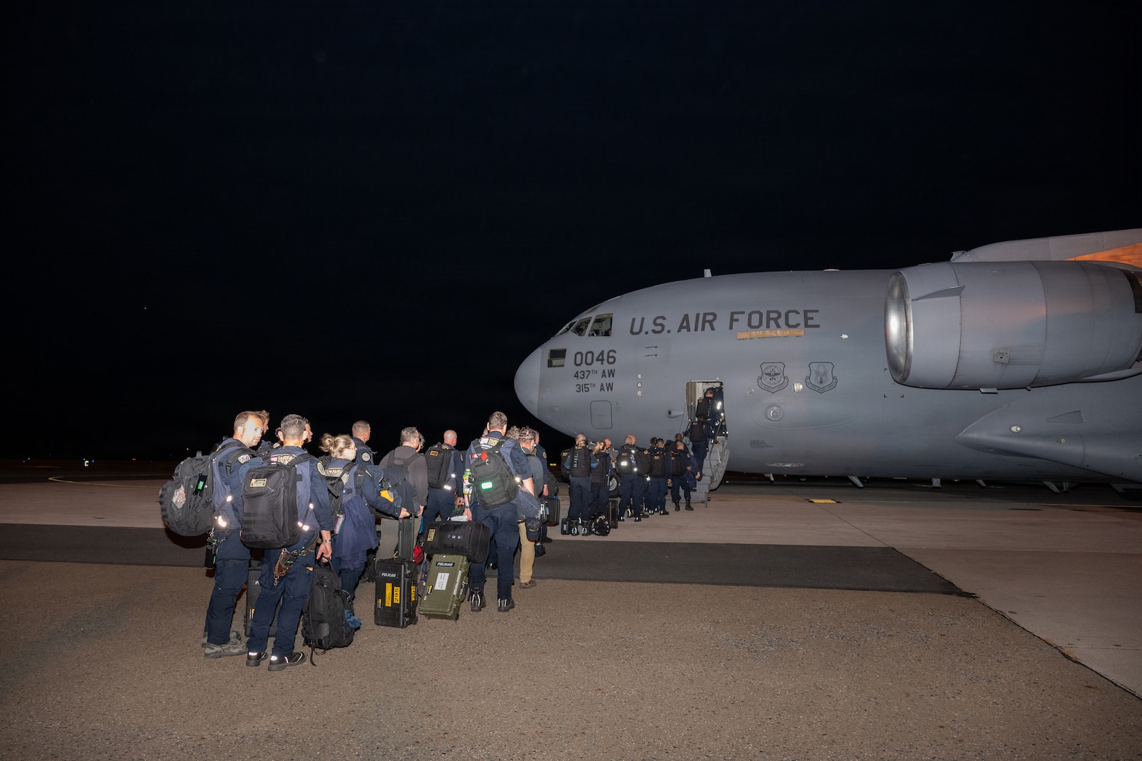 A line of personnel board a military aircraft.