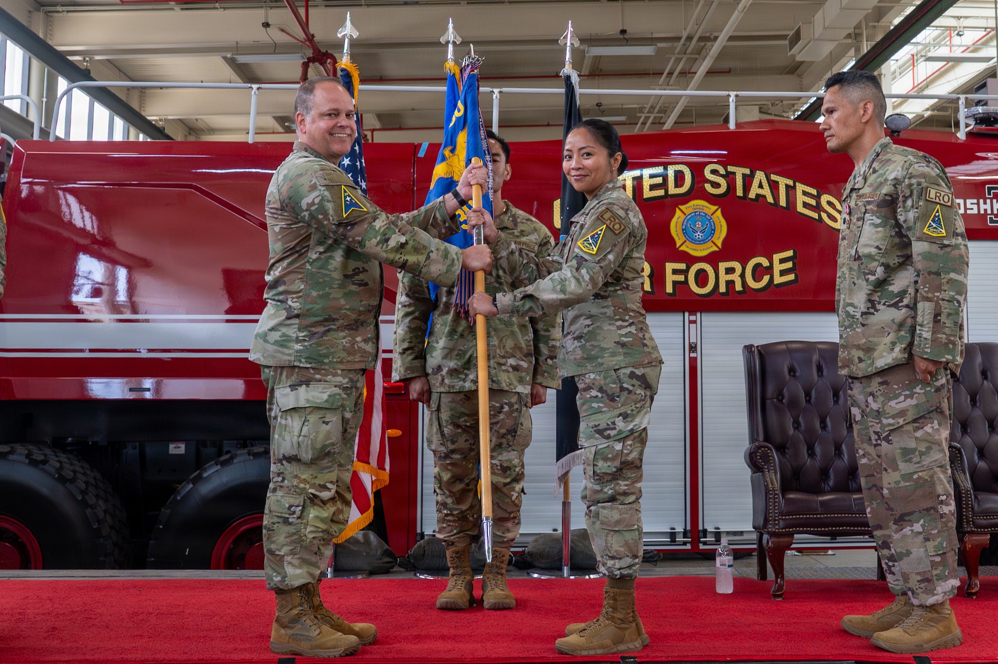 Two people stand and hold a flag on a stage