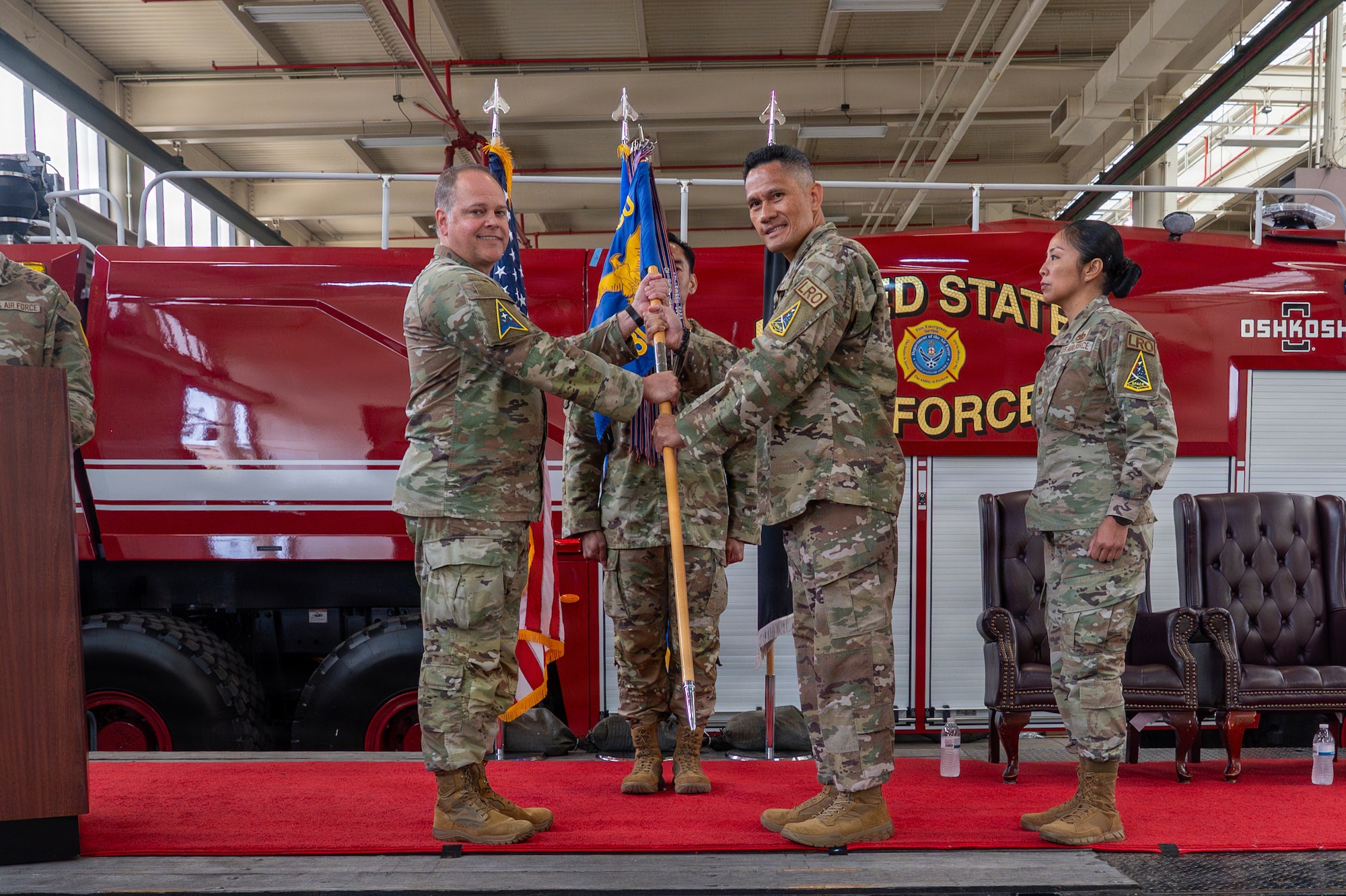 Two people stand and hold a flag on a stage