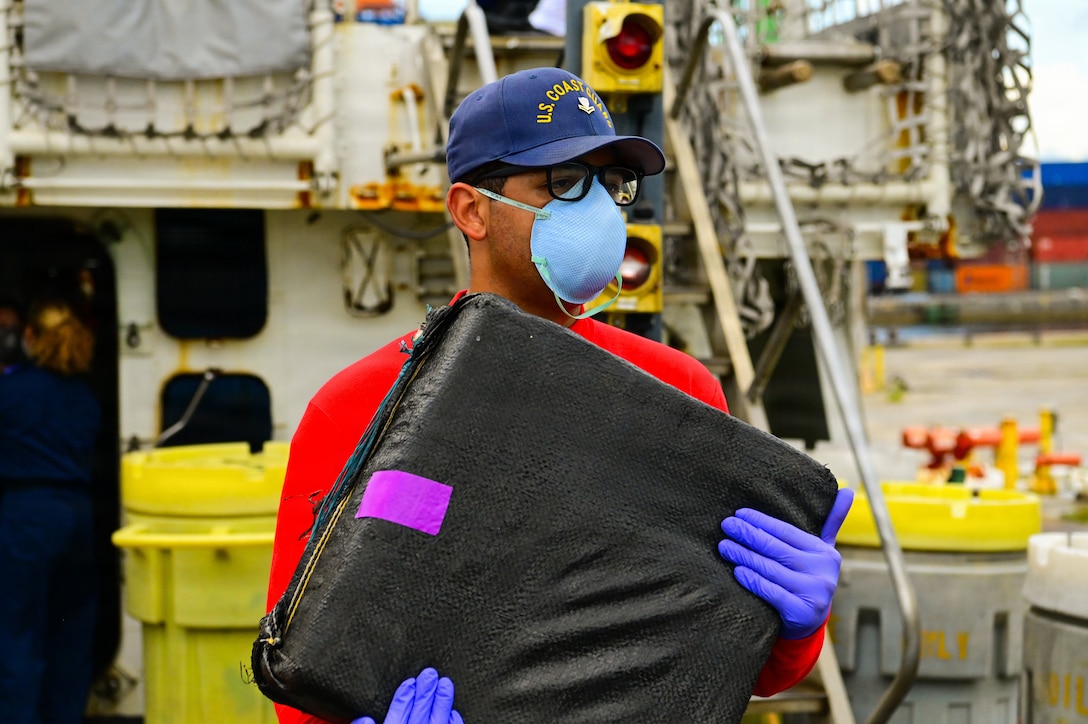 A crew member aboard USCGC Bear (WMEC 901) carries a bale of cocaine during a drug offload of illegal narcotics valued at more than $63 million at Port Everglades, Florida June 26,2026. The seized contraband was the result of three interdictions in international waters of the Eastern Pacific Ocean. (U.S. Coast Guard Photo by Seaman Christopher Moret)