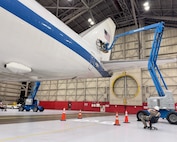 A team comprised of Airmen and civilians assigned to the 95th Maintenance Group apply a Square B vinyl applique