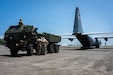 A military vehicle prepares to back into an aircraft