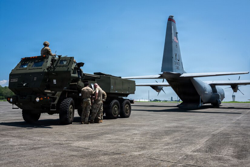 A military vehicle prepares to back into an aircraft