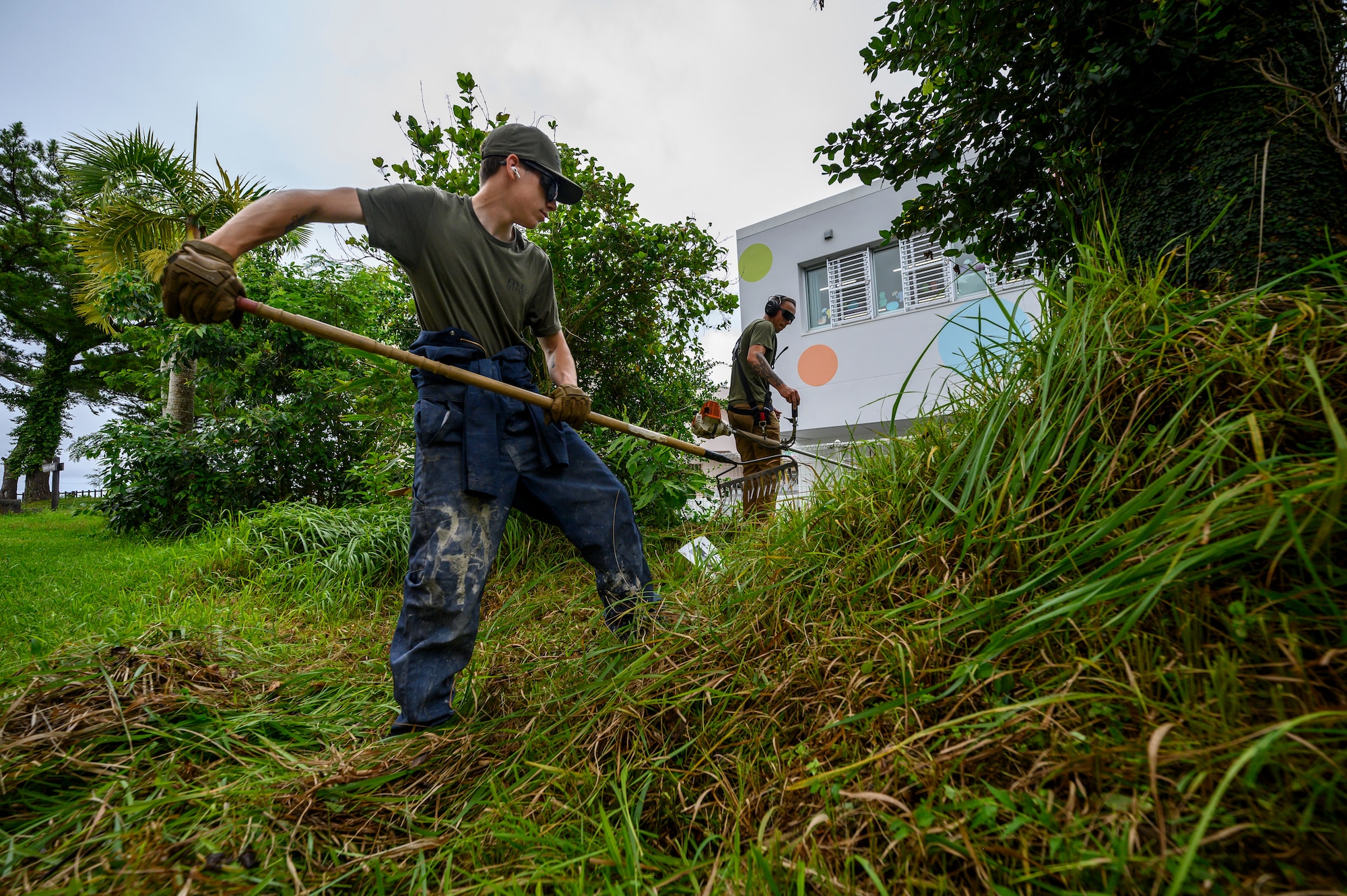 U.S. Air Force Airmen assigned to the 18th Civil Engineer Group clear overgrown vegetation during a volunteer cleanup project at Misato Children’s Home in Okinawa, Japan, June 12, 2026. The effort helped improve the safety and appearance of the facility while strengthening community ties between Kadena Air Base and local residents. (U.S. Air Force photo by Airman 1st Class Francisco Huerta)