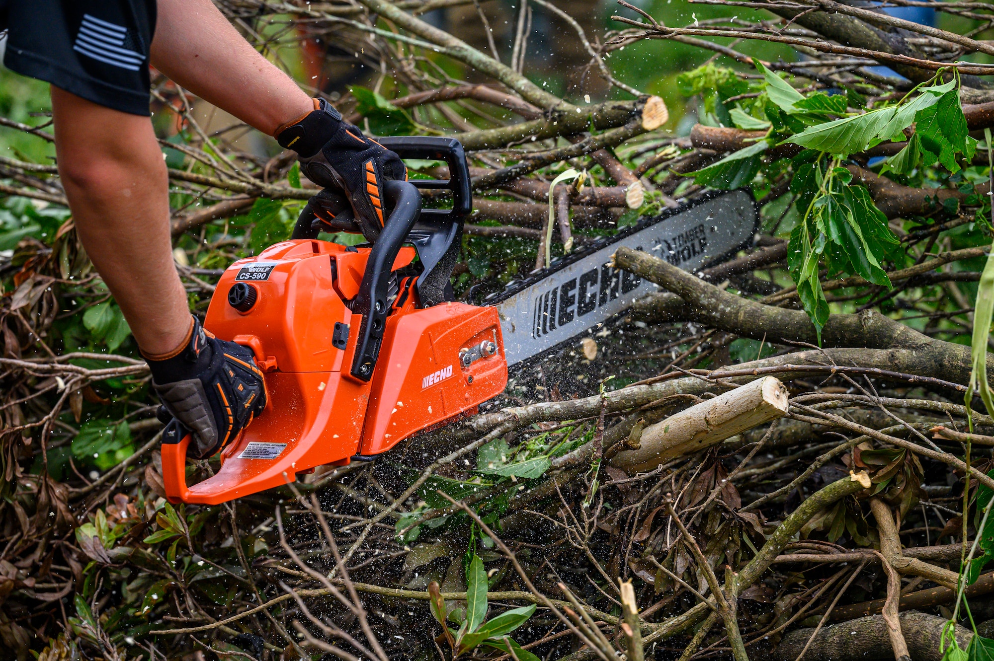A volunteer cuts through storm-damaged vegetation during a volunteer cleanup project at Misato Children’s Home in Okinawa, Japan, June 12, 2026. Volunteers removed debris left behind by Typhoon Jangmi to help restore safe outdoor spaces for children. (U.S. Air Force photo by Airman 1st Class Francisco Huerta)