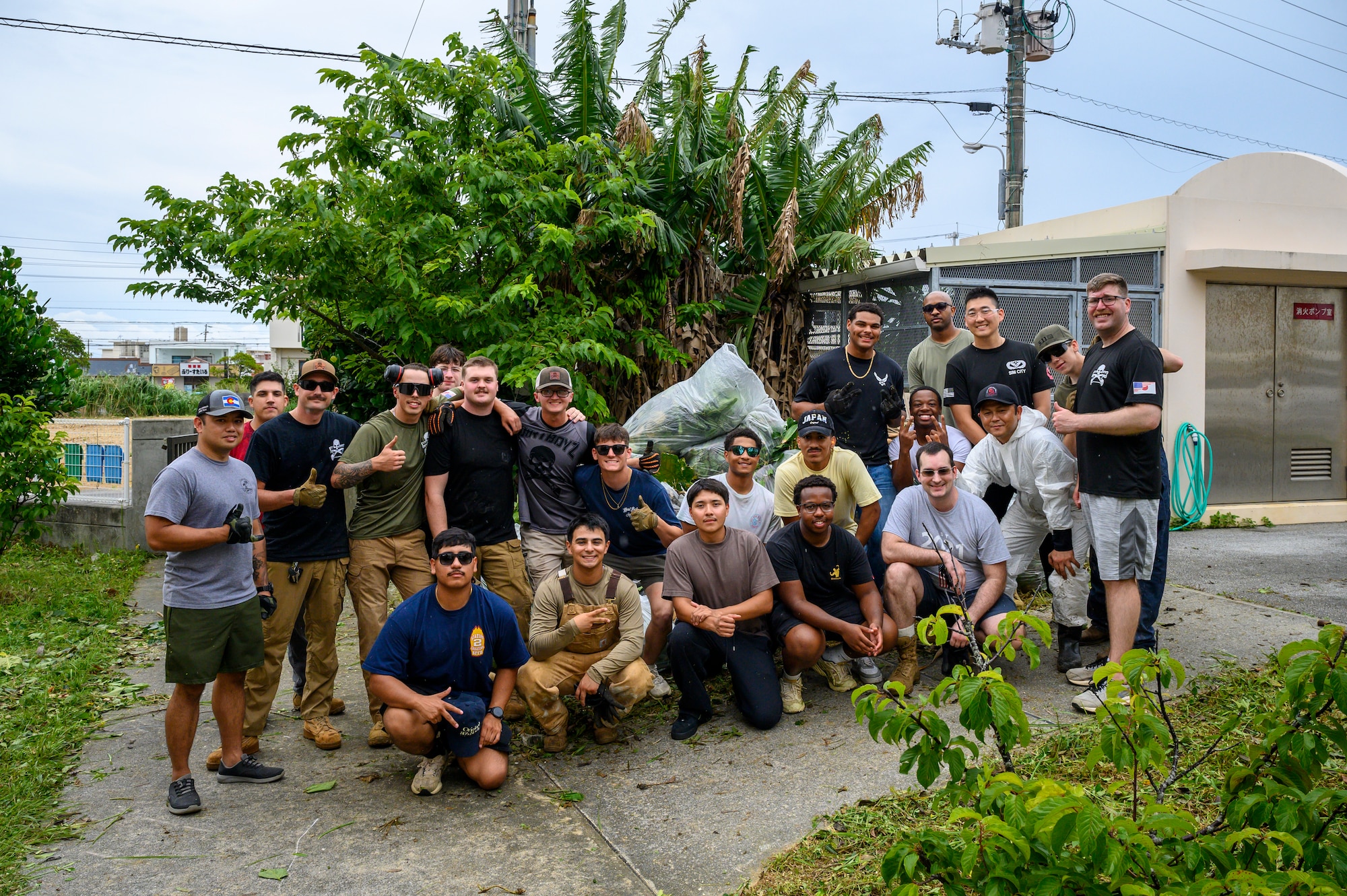 Volunteers pose for a group photo in front of debris collected during a cleanup project at Misato Children’s Home in Okinawa, Japan, June 12, 2026. Members of the Kadena Top III organized the event to support the local community and strengthen relationships with Okinawan residents. (U.S. Air Force photo by Airman 1st Class Francisco Huerta)