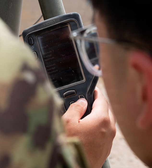 U.S. Air Force radar, airfield, and weather systems technicians assigned to the 776th Air Expeditionary Base Squadron checks wind speed and direction settings on a Vaisala handheld weather device, part of the AN/TMQ-53 Tactical Meteorological Observing System, at Chabelley Airfield, Djibouti, May 19, 2026. Accurate weather readings are essential for the safety of all airfield and flight operations. (U.S. Air Force photo by Senior Airman Luis Gomez)