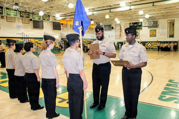 Hospital Corpsman 1st Class Reginald Smalls, assigned to Navy Medicine Readiness and Training Command (NMRTC) Patuxent River, inspects a Navy Junior Reserve Officers Training Corps (NJROTC) platoon guidon bearer during the Annual Military Inspection (AMI) at Great Mills High School. Smalls served as a guest inspector for the event, evaluating cadets on their military bearing, uniform appearance, and general knowledge, highlighting the command's commitment to community mentorship.