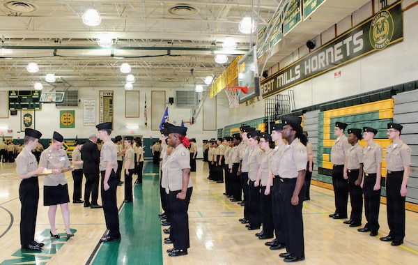 Hospital Corpsman 2nd Class Elizabeth Basham, assigned to Navy Medicine Readiness and Training Command (NMRTC) Patuxent River, inspects a Navy Junior Reserve Officers Training Corps (NJROTC) cadet during the Annual Military Inspection (AMI) at Great Mills High School. Basham served as a guest inspector for the event, evaluating cadets on military bearing, uniform appearance, and general knowledge as part of the command's commitment to community outreach and mentorship.