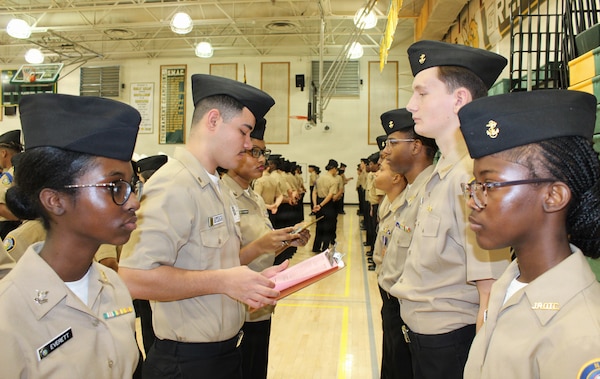Hospitalman 3rd Class Lucas Artega, assigned to Navy Medicine Readiness and Training Command (NMRTC) Patuxent River, quizzes a Navy Junior Reserve Officers Training Corps (NJROTC) cadet on naval history during the Annual Military Inspection (AMI) at Great Mills High School. Artega served as a guest inspector for the event, evaluating cadets on their military bearing, uniform appearance, and general knowledge as part of a larger community outreach initiative.