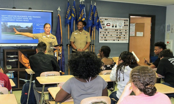 Chief Petty Officer Amber Ronquille, assigned to Navy Medicine Readiness and Training Command (NMRTC) Patuxent River, discusses the command's detachment at Indian Head during a presentation to Air Force Junior Reserve Officers Training Corps (AFJROTC) cadets at Chopticon High School, as Hospital Corpsman 2nd Class Ifeoluwapo Olayemi looks on. The engagement was part of a spring semester outreach initiative focused on leadership, professional development, and showcasing the diverse roles within Navy Medicine to the next generation of potential service members.