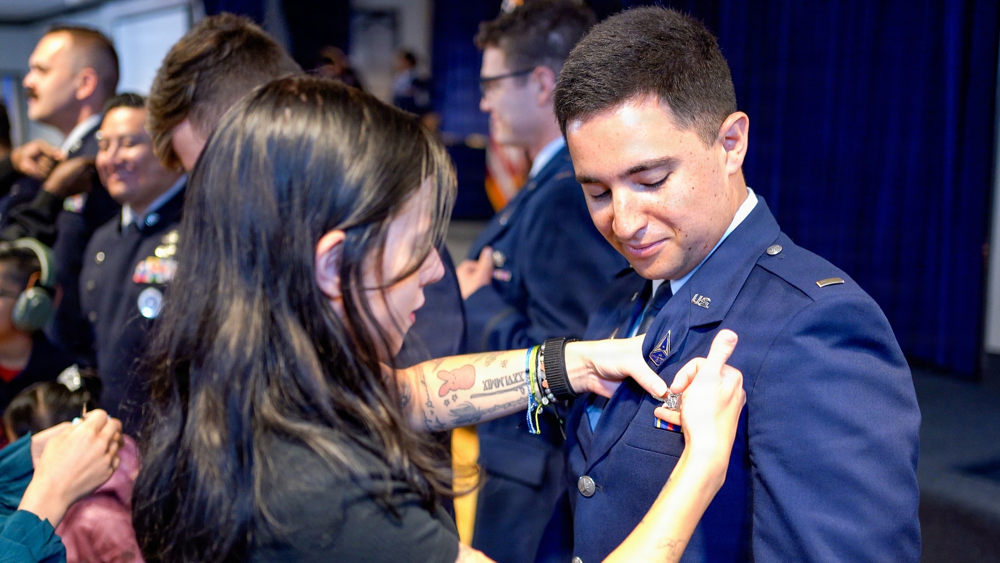 A U.S. Space Force Guardian officer has a lapel pin pinned onto their uniform by a loved one during an Officer Training Course graduation ceremony at Peterson Space Force Base, Colorado, June 26, 2026.
