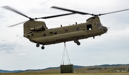A CH-47 Chinook helicopter assigned to the 1st Battalion (General Support Aviation), 189th Aviation Regiment transports an MEP-806 power generator by sling load during a joint field training exercise at Fort Harrison, Montana, June 26, 2026.