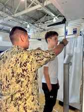 Hospital Apprentice Daniel Luna, assigned to U.S. Naval Hospital Rota, measures the height of a Department of War Education Activity (DoWEA) student athlete during a sports physical rodeo at David Glasgow Farragut Middle High School, Naval Station Rota, Spain, June 02, 2026. During the event, U.S. Naval Hospital Rota staff completed more than 169 sports physicals, improving access to care for military families and helping students meet participation requirements for the 2026–2027 school year. (U.S. Navy photo by Lt. Cmdr. Alicia Sacks)