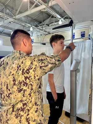 Hospital Apprentice Daniel Luna, assigned to U.S. Naval Hospital Rota, measures the height of a Department of War Education Activity (DoWEA) student athlete during a sports physical rodeo at David Glasgow Farragut Middle High School, Naval Station Rota, Spain, June 02, 2026. During the event, U.S. Naval Hospital Rota staff completed more than 169 sports physicals, improving access to care for military families and helping students meet participation requirements for the 2026–2027 school year. (U.S. Navy photo by Lt. Cmdr. Alicia Sacks)
