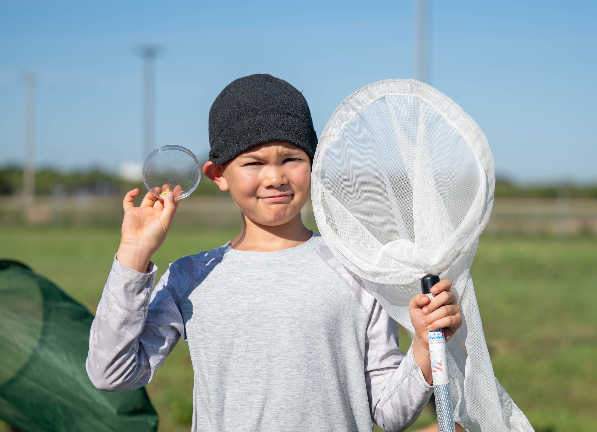 A child displays an insect observation container and net during BioBlitz at Altus Air Force Base (AFB), Oklahoma, June 17, 2026. The net and container allowed children to have educational fun while identifying various insects around Altus AFB. (U.S. Air Force photo by Airman 1st Class Emma Wright)
