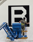 A team comprised of Airmen and civilians assigned to the 95th Maintenance Group apply an edge sealant to a Square B vinyl applique