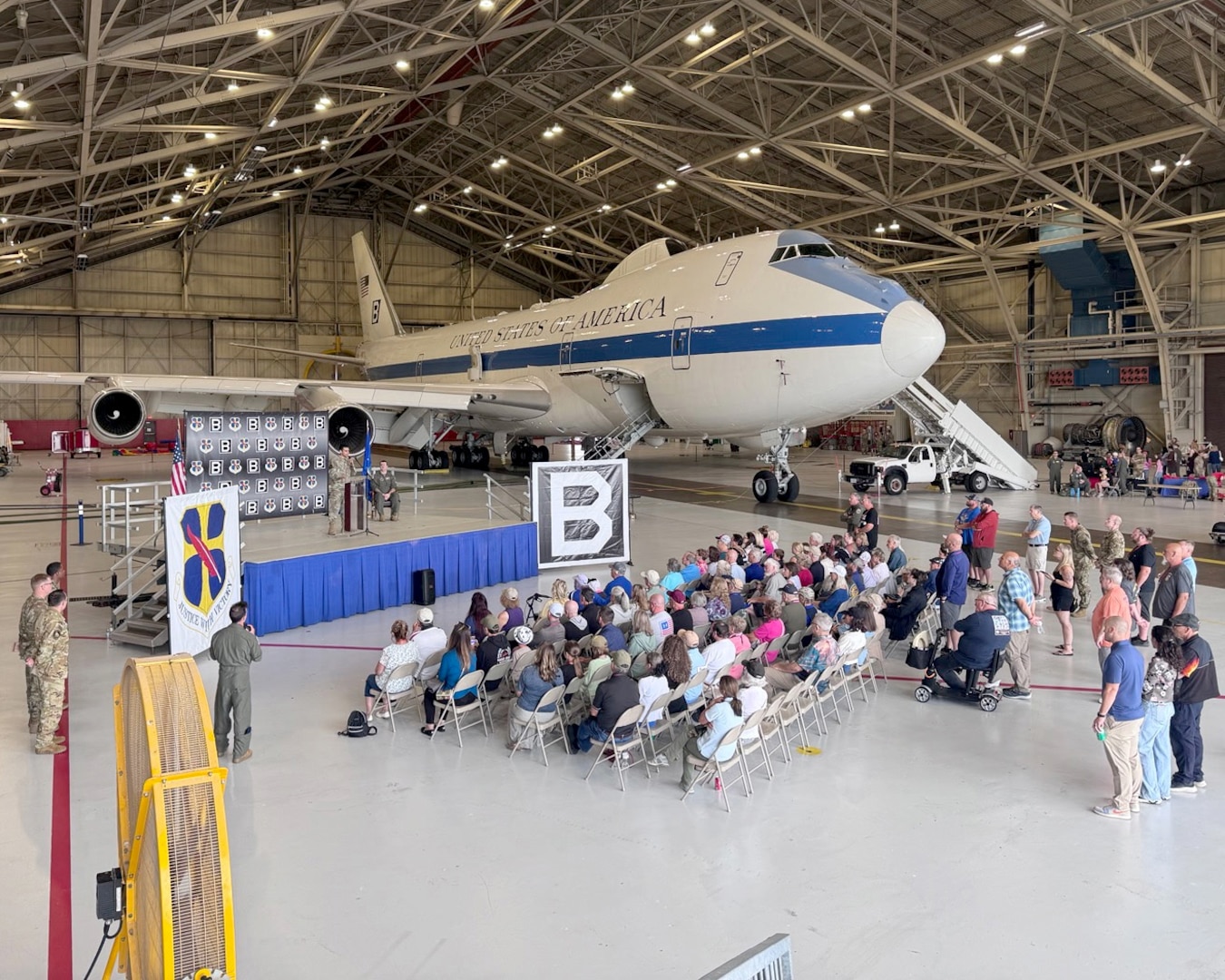 A crowd sits in front of an E-4B