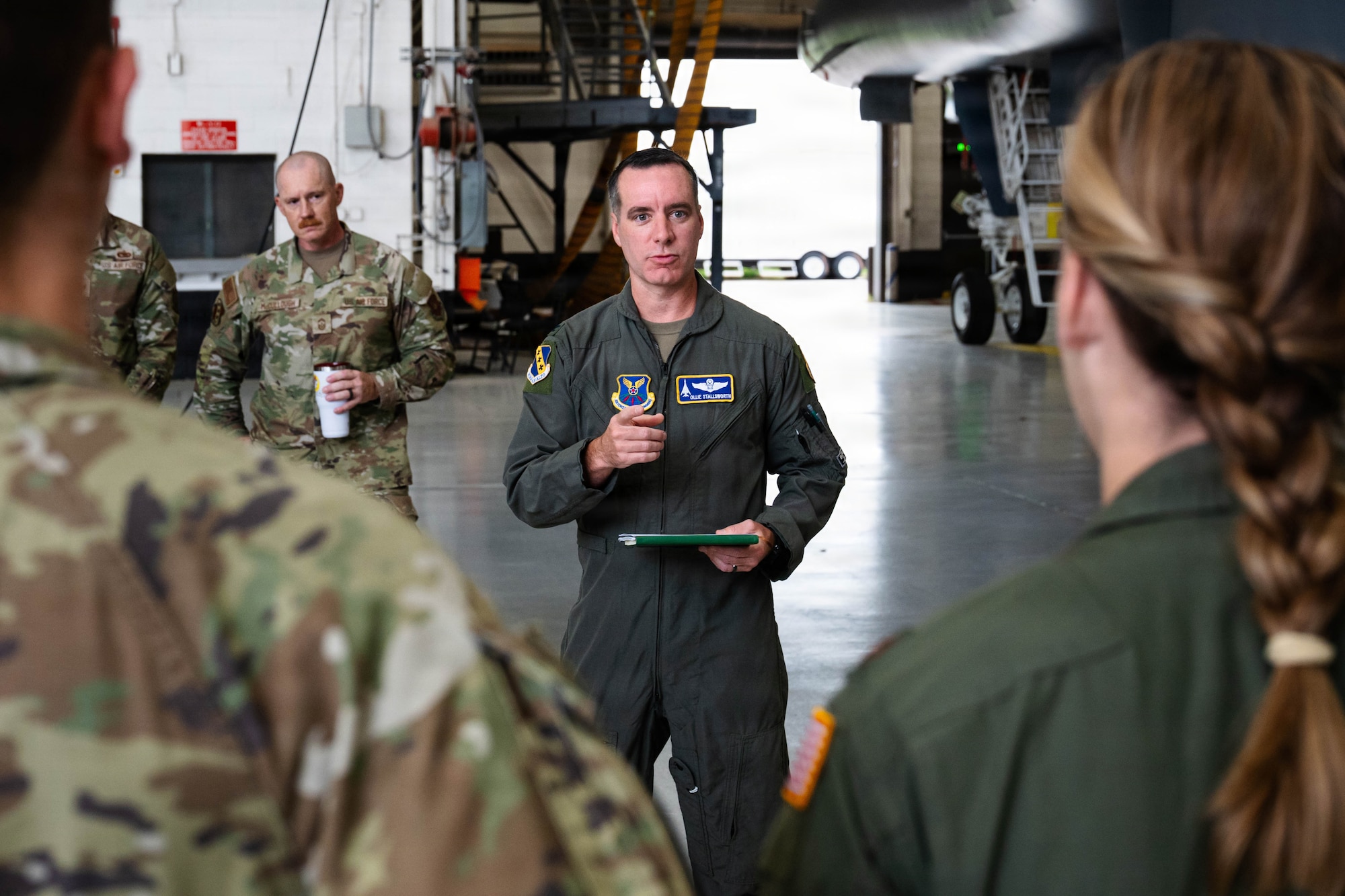 Airmen and civilians stand in a group and receive a brief