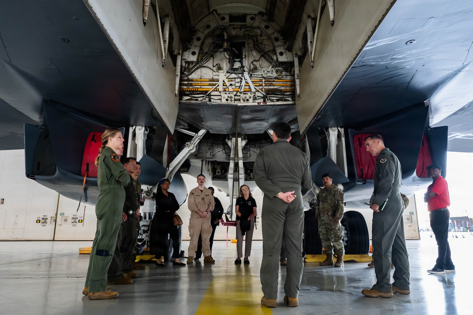 Airmen and civilians stand in a group and receive a brief