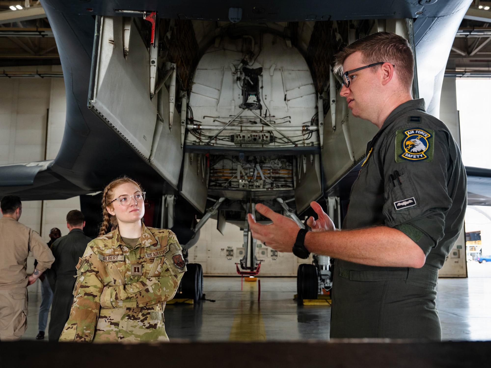 Airmen and civilians stand in a group and receive a brief