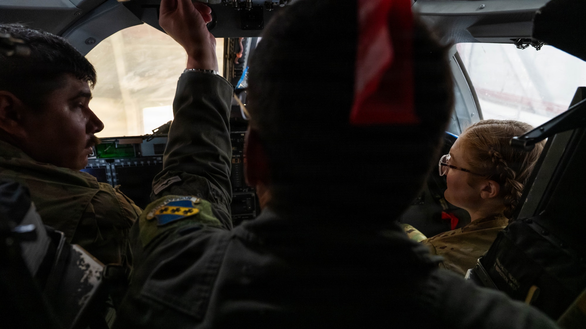 Airmen and civilians stand in a group and receive a brief