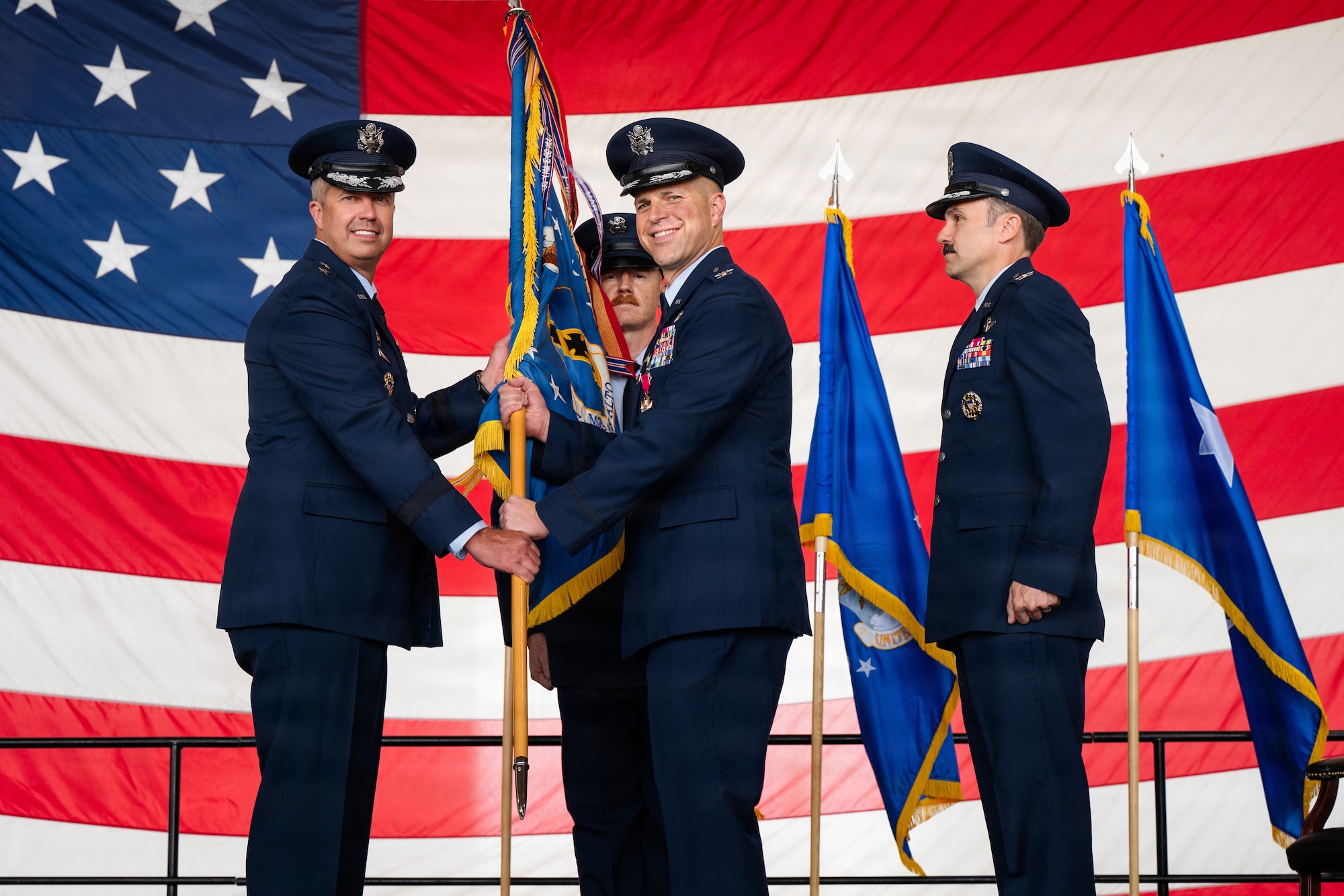 Airmen stand on stage during a formal Change of Command Ceremony