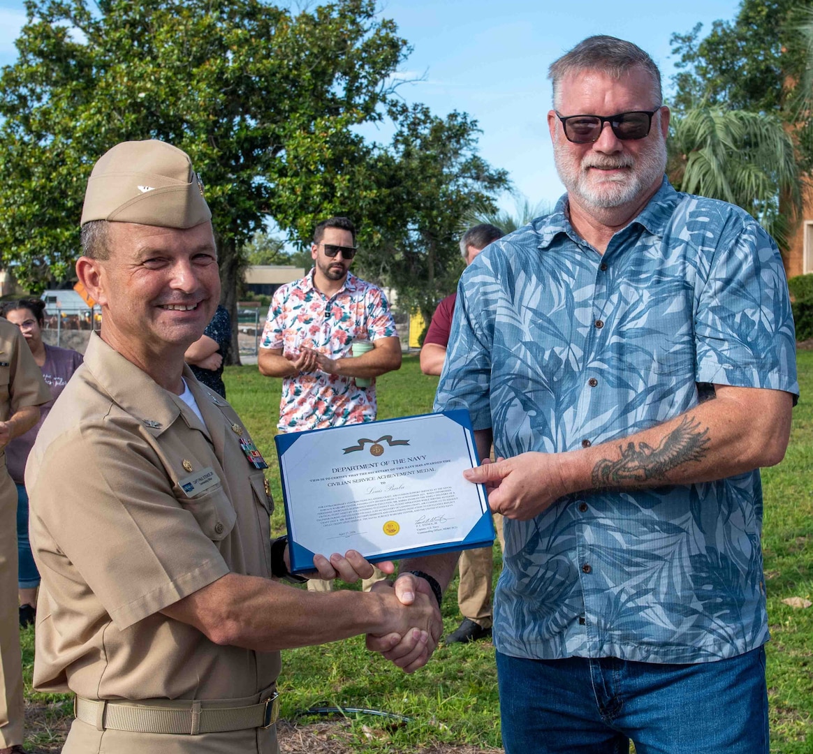 (left) Capt. Paul Stence, Jr., Naval Surface Warfare Center Panama City Division (NSWC PCD) commanding officer, recognizes Louis Barba, NSWC PCD Assault Craft Unit 5 Ship to Shore Connector pilot, with the Department of the Navy Civilian Service Achievement Medal for ensuring critical assets were delivered on time to the fleet, June 12. Accepting the award on his behalf was Skip Whitmore, NSWC PCD Landing Craft Air Cushion Support Services project manager. (U.S. Navy photo by Eddie Green)
