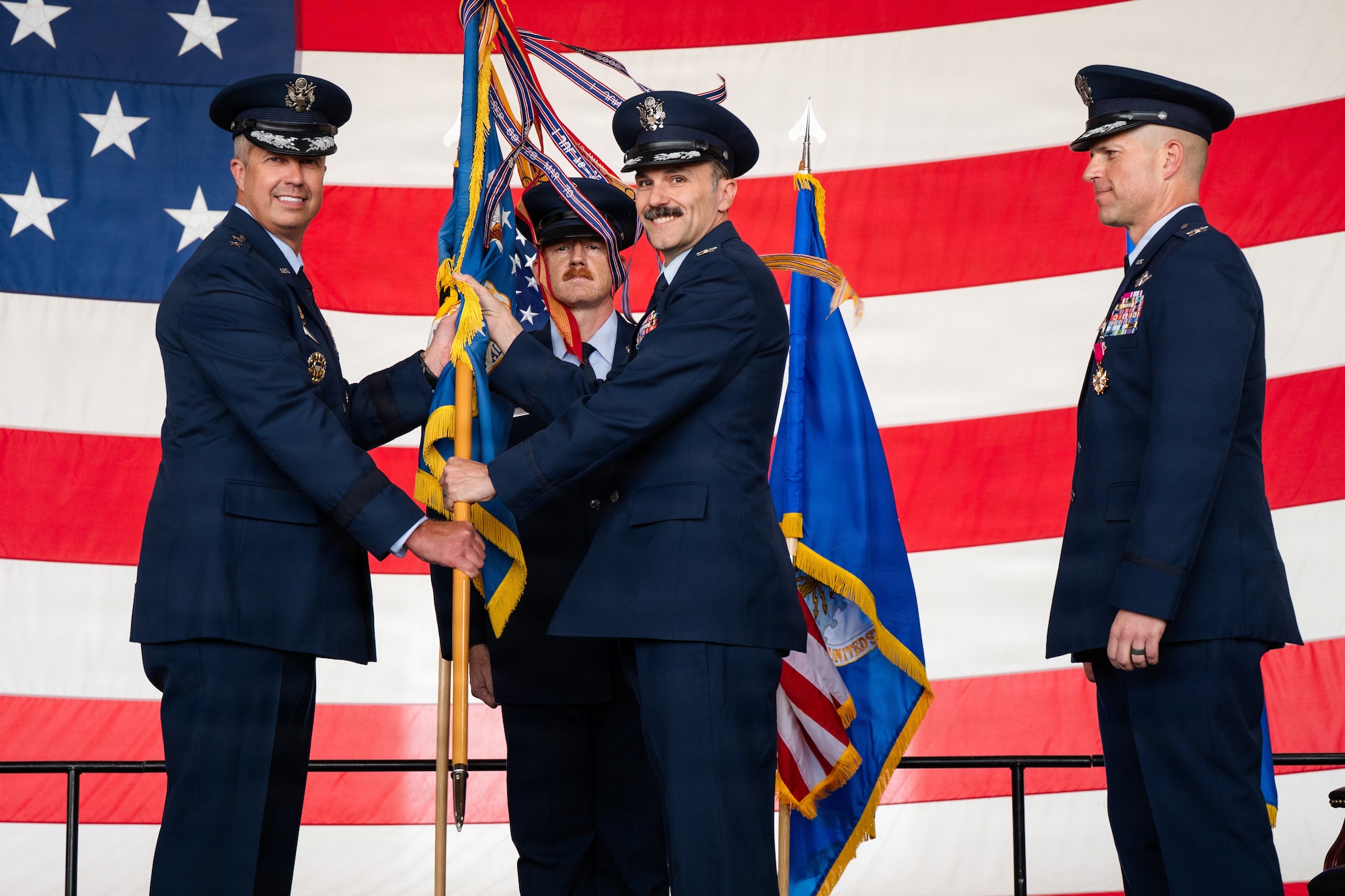 Airmen stand on stage during a formal Change of Command Ceremony