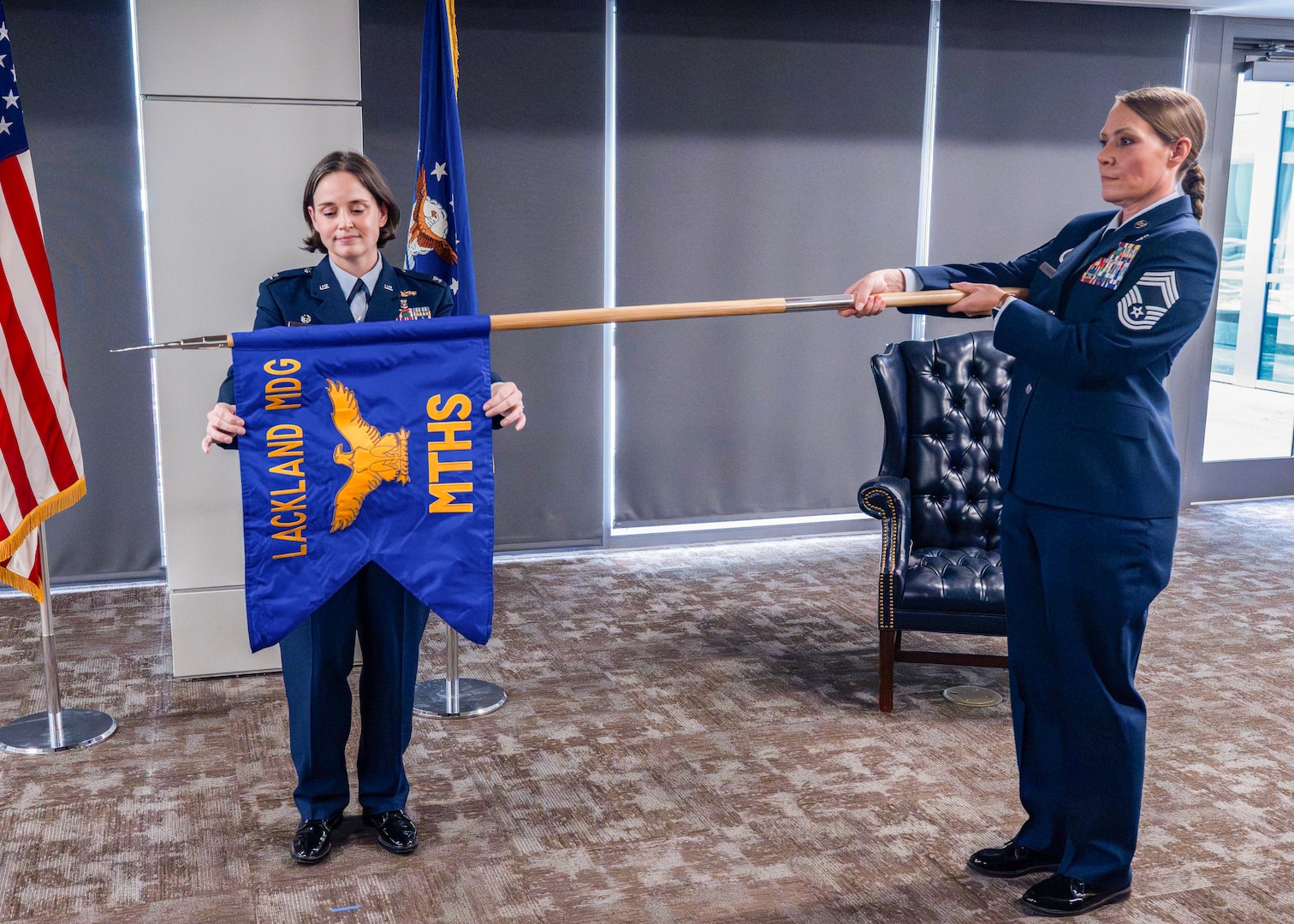 U.S. Air Force Col. Shawn Garcia, commander of the Lackland Medical Group, and Chief Master Sgt. Codi Bowman, senior enlisted leader of the Lackland Mental Health Squadron, unfurl the squadron guidon during the unit's activation ceremony at Wilford Hall Ambulatory Surgical Center, Joint Base San Antonio-Lackland, Texas, June 25, 2026.