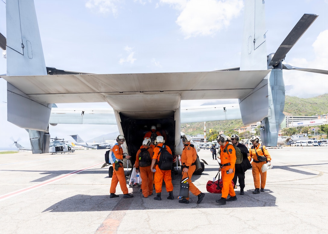 People in orange suits board a military aircraft.