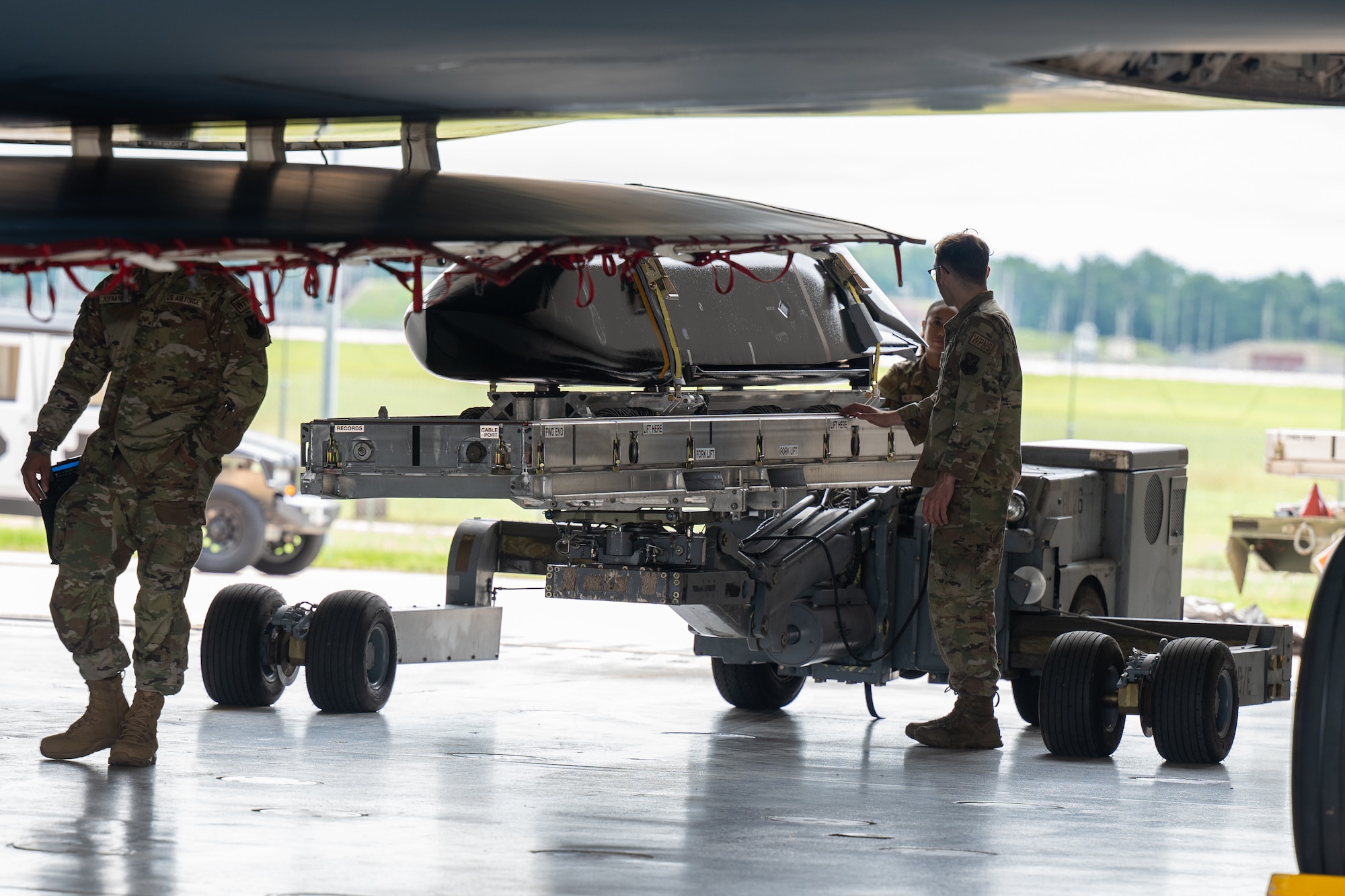 A cruise missile is loaded onto a stealth bomber