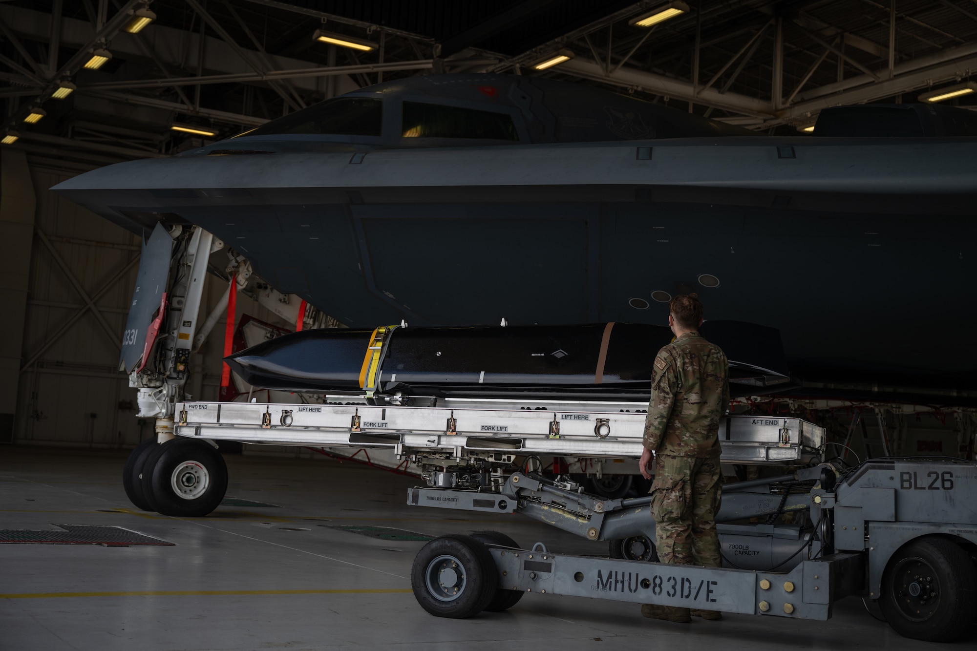 A cruise missile is loaded onto a stealth bomber