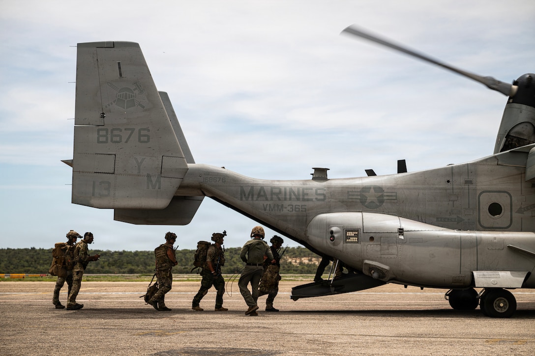 Troops board the back of a military aircraft.