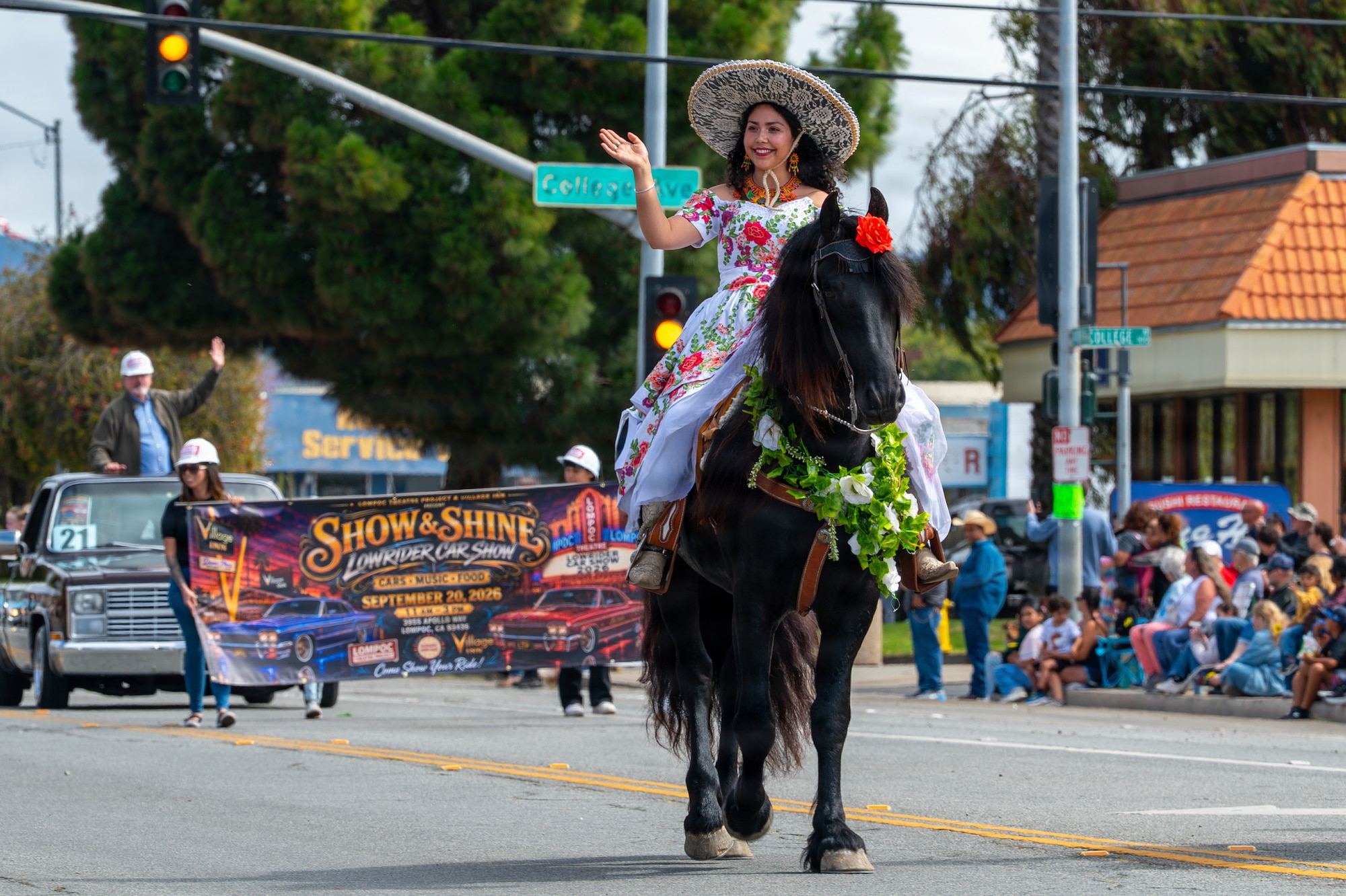 A person rides a horse and waves at a crowd