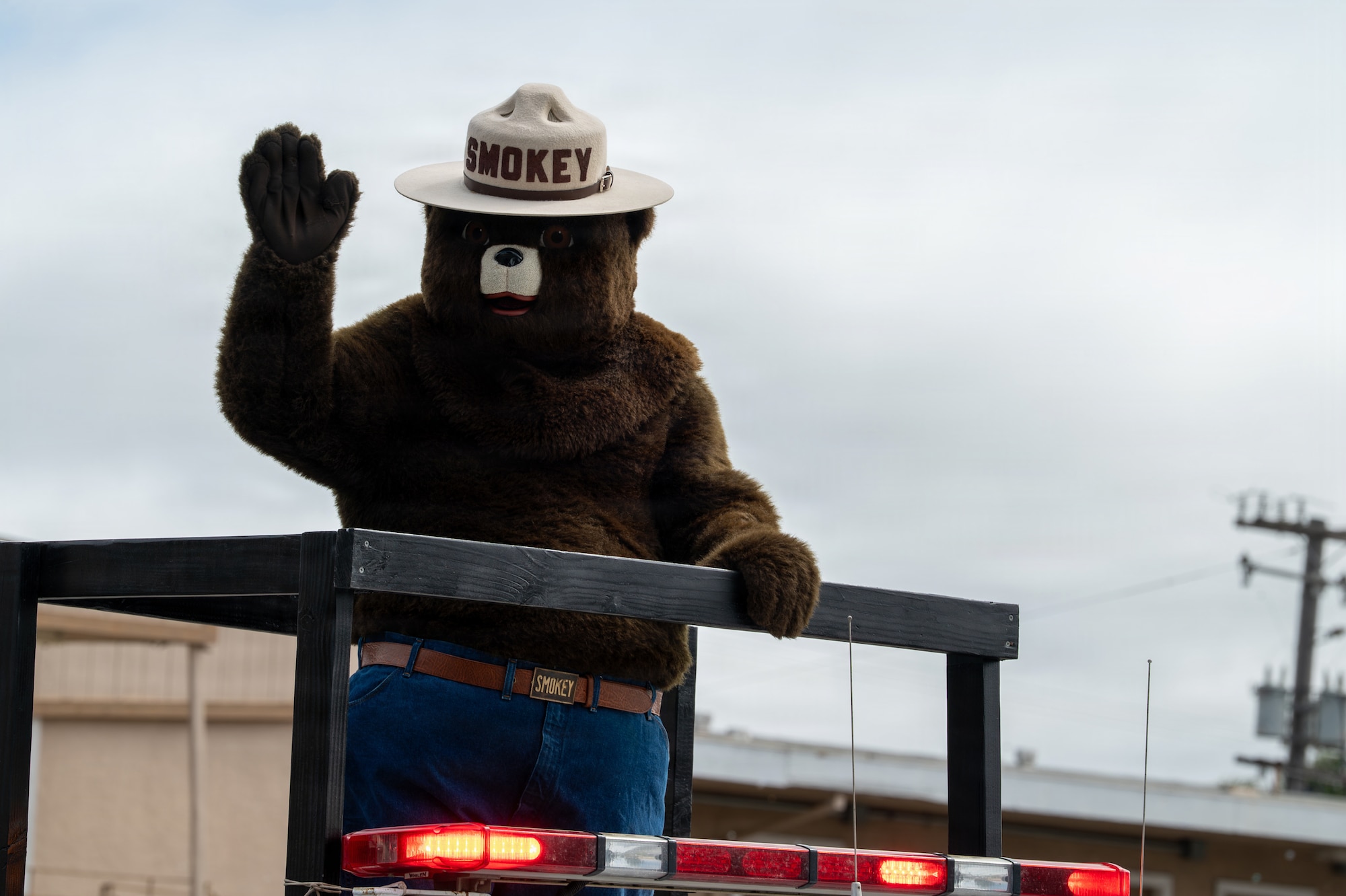 A bear mascot waves as they stand on a parade float