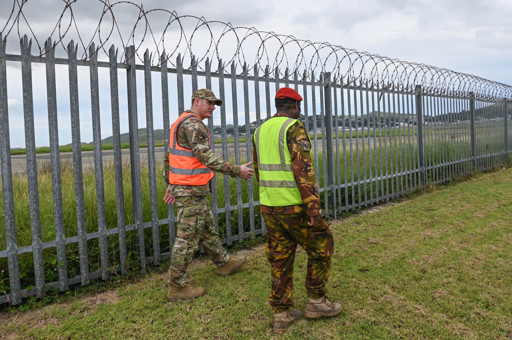 U.S. Air Force Senior Master Sgt. Nathan Silvers, assigned to Volk Field, Wisconsin Air National Guard, left, and Papua New Guinea Defence Force Corporal Arthur Wariambu, assigned to the PNGDF Air Transport Wing, walk along a fence that guards the airfield at the PNGDF Air Transport Wing, in the National Capital District, Port Moseby, PNG March 14, 2025. The Wisconsin National Guard State Partnership Program is working with the U.S. Embassy team in PNG, and the PNG Defence Force on a consolidated exchange in PNG during fiscal year 2025 that includes four subject matter expert exchanges. (U.S. Air National Guard photo by Master Sgt. Mary Greenwood)