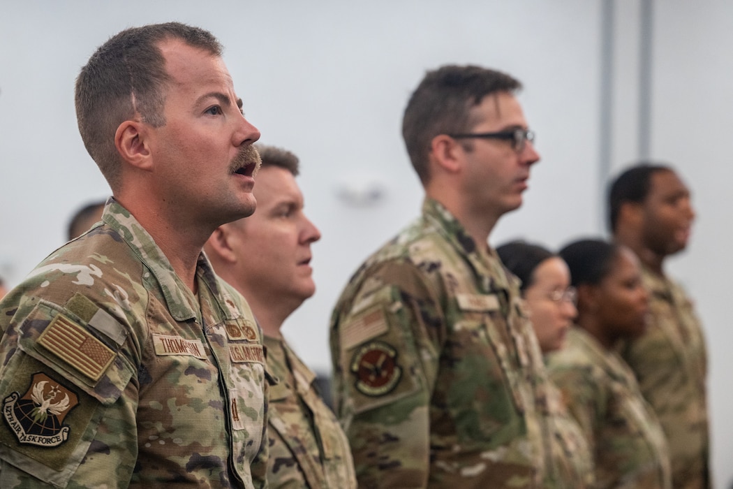 Military members are standing and singing along at attention.