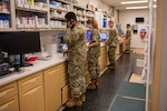 Four service members stand in a military pharmacy.