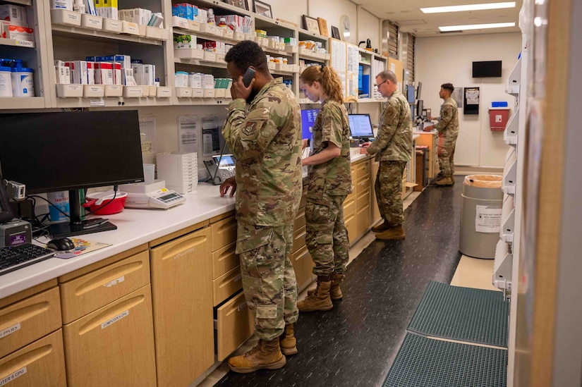 Four service members stand in a military pharmacy.