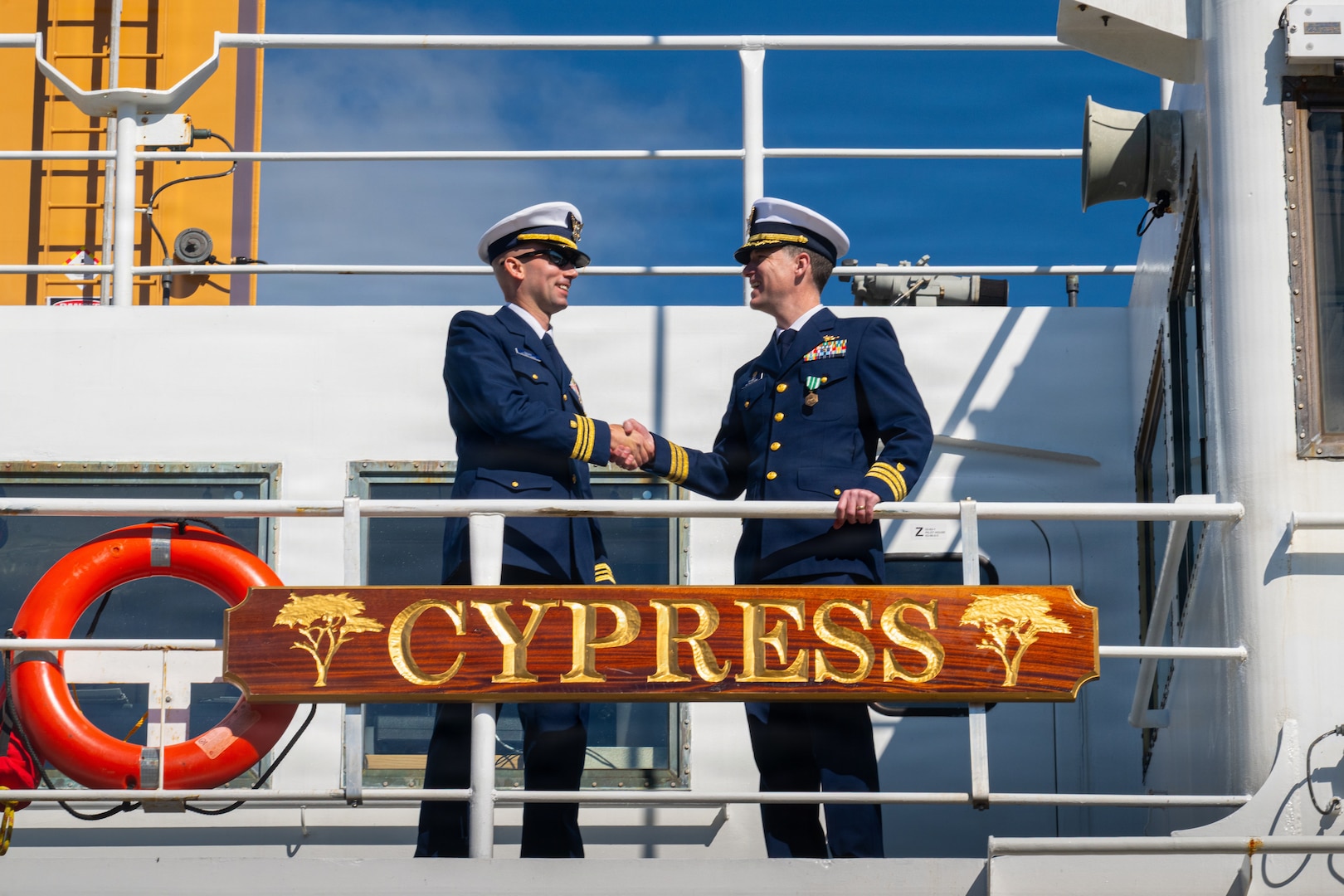 Coast Guard Lt. Cmdr. Austin Condra (left), incoming commanding officer of Coast Guard Cutter Cypress (WLB 210), shakes hands with Cmdr. James Toohey (right), outgoing commanding officer of the Cypress, following the cutter’s change of command ceremony in Kodiak, Alaska, June 9, 2026. Condra assumed command from Toohey following his tour as commanding officer.
(U.S. Coast Guard photo by Petty Officer 3rd Class Nathan Bishop)