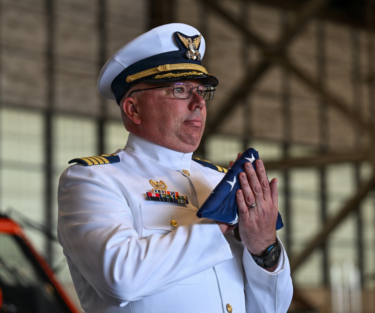 Coast Guard Capt. Timothy Williams, outgoing commanding officer of Coast Guard Air Station Kodiak, holds a folded flag that was presented to him during the change of command ceremony at Hangar Three in Kodiak, Alaska, June 26, 2026. Change of command ceremonies are a time-honored tradition that represent the passing of authority from one commanding officer to the next. (U.S. Coast Guard photo by Petty Officer 3rd Class Rylan Singleton)