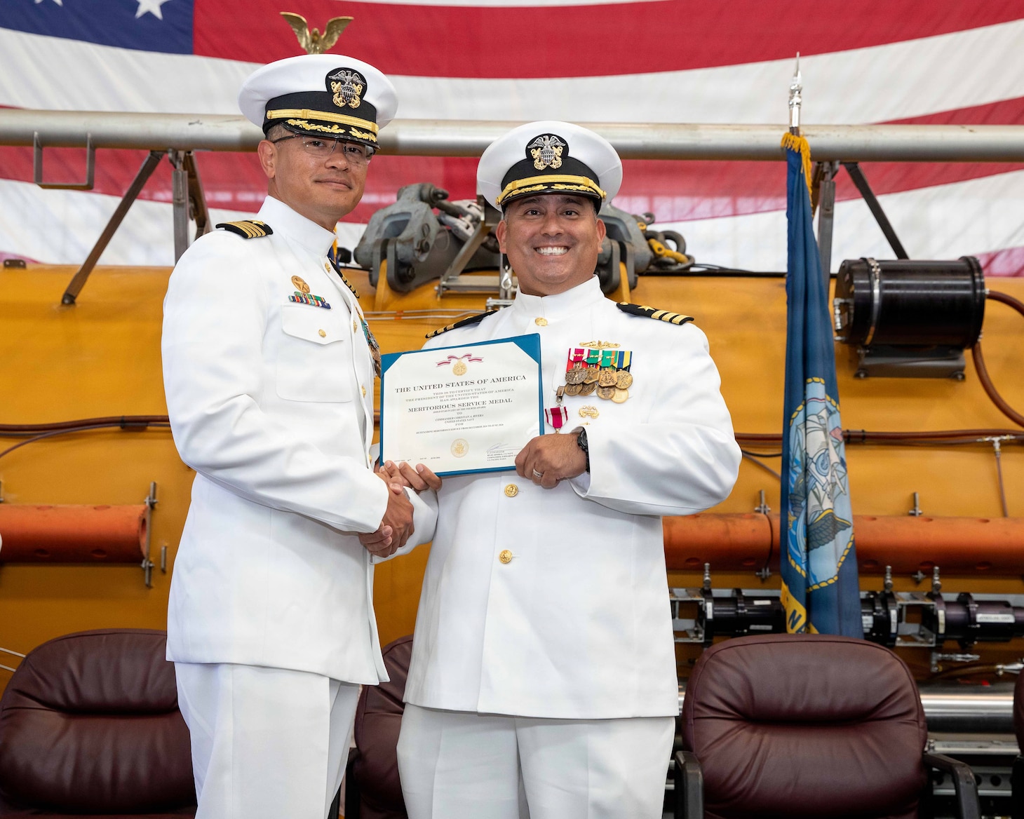 NAVAL AIR STATION NORTH ISLAND, Calif. (June 26, 2026) Capt. Phillip Sylvia Jr., commander, Submarine Squadron 11, left, presents a Meritorious Service Medal to Cmdr. Christian Rivera during the change of command ceremony for Undersea Rescue Command (URC) onboard Naval Air Station North Island, June 26, 2026. During the ceremony, Rivera was relieved by Cmdr. Michael Mowry as commanding officer of URC.  URC, comprised of active and Reserve component Sailors, and civilian contractors, is the Navy’s only submarine rescue-capable command ready to deploy around the world in the event of a submarine emergency. (U.S. Navy photo by Mass Communication Specialist 2nd Class Rashan Jefferson)