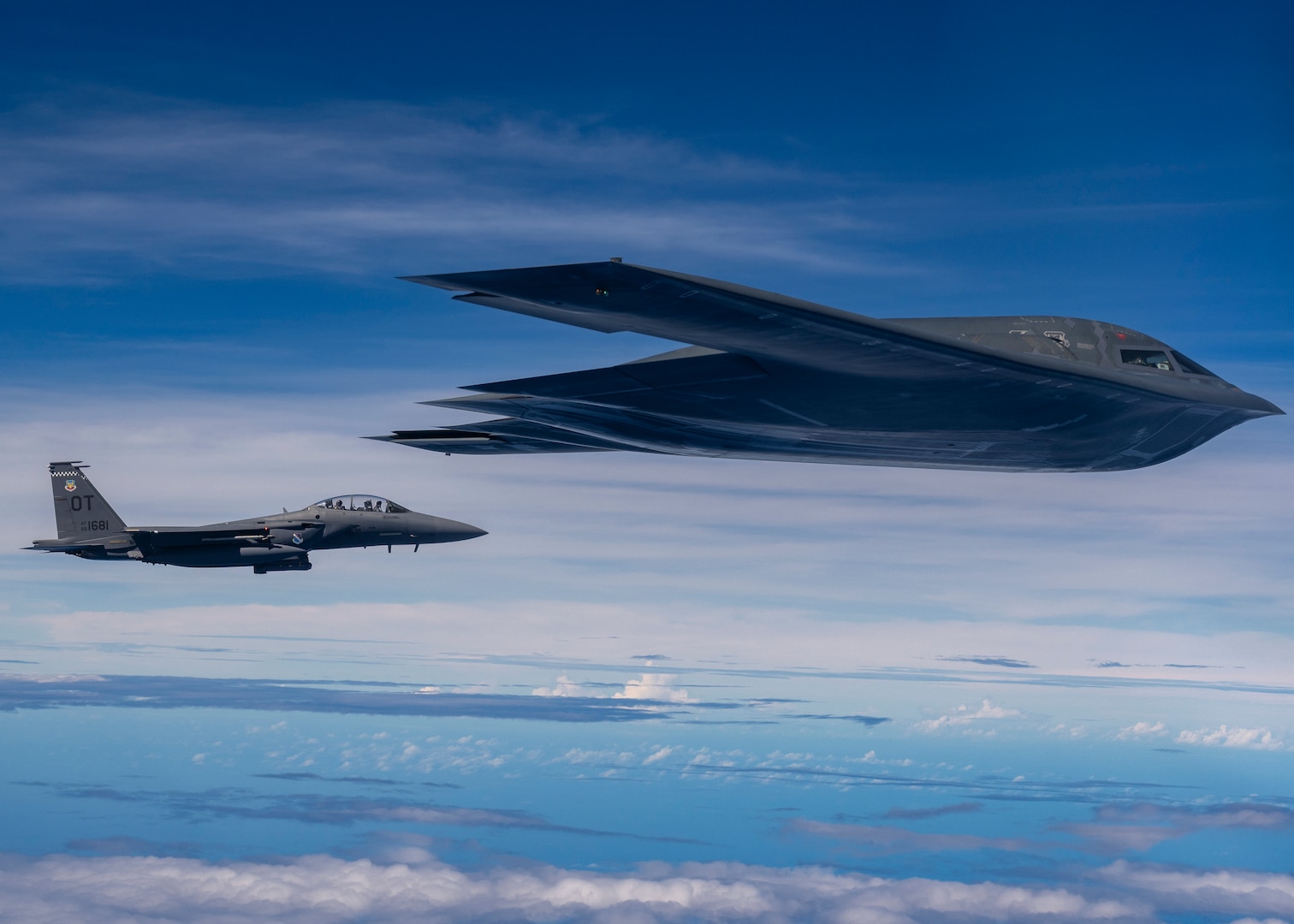 A fighter jet and stealth bomber fly together