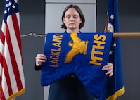 U.S. Air Force Col. Shawn Garcia, commander of the Lackland Medical Group, unfurls the newly activated Lackland Mental Health Squadron guidon during an activation ceremony at Wilford Hall Ambulatory Surgical Center, Joint Base San Antonio-Lackland, Texas, June 25, 2026.