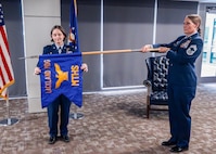 U.S. Air Force Col. Shawn Garcia, commander of the Lackland Medical Group, and Chief Master Sgt. Codi Bowman, senior enlisted leader of the Lackland Mental Health Squadron, unfurl the squadron guidon during the unit's activation ceremony at Wilford Hall Ambulatory Surgical Center, Joint Base San Antonio-Lackland, Texas, June 25, 2026.